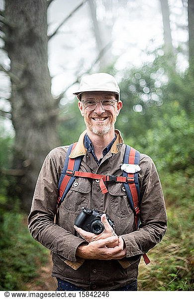 Lächelnder Fotograf mit Kamera im Nebelwald