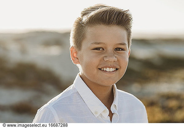 Lächelnder  gepflegter Junge in weißem Hemd mit Knopfleiste