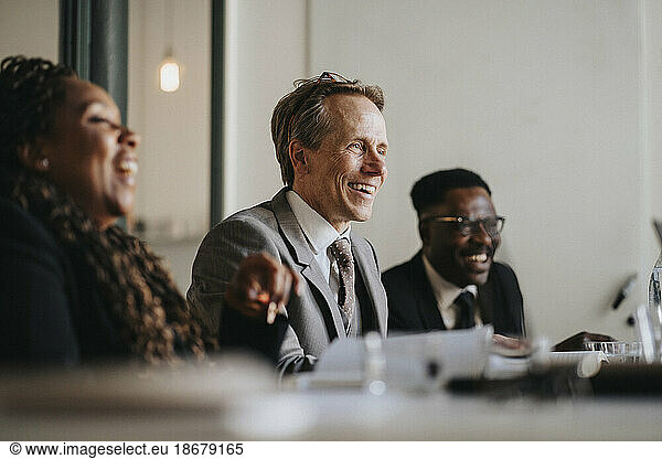 Lächelnder Geschäftsmann  der mit Kollegen während einer Besprechung im Büro diskutiert