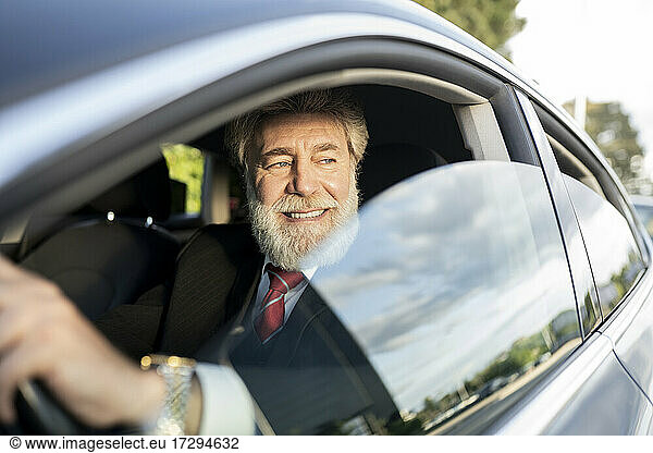 Lächelnder Geschäftsmann schaut durch ein Autofenster