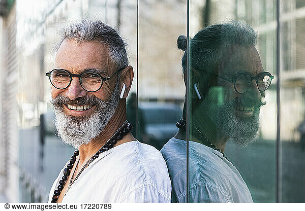 Lächelnder Hipster-Mann vor einer Glaswand