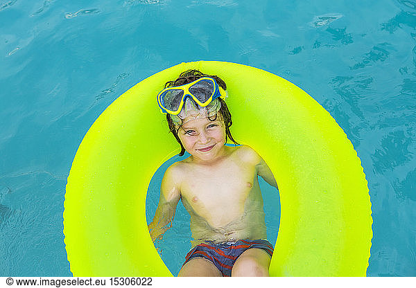 Lächelnder 5-jähriger Junge in farbenfrohem Floatie im Wasser