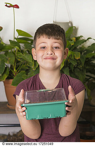 Lächelnder Junge hält Blumentopf-Box zu Hause