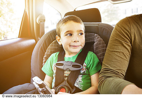 Lächelnder Junge sitzt an einem sonnigen Tag im Autositz