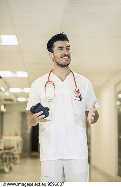 Lächelnder junger Arzt gestikuliert im Krankenhaus