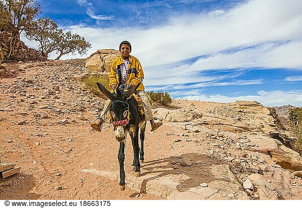 Lächelnder junger Mann  der auf einem Esel reitet  Petra  Jordanien  Asien