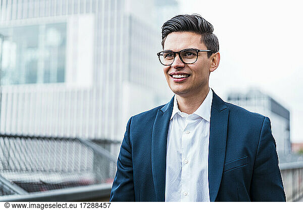 Lächelnder männlicher Berufstätiger mit Brille  der wegschaut