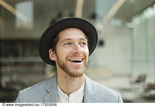 Lächelnder männlicher Berufstätiger mit Hut in Hutoptik
