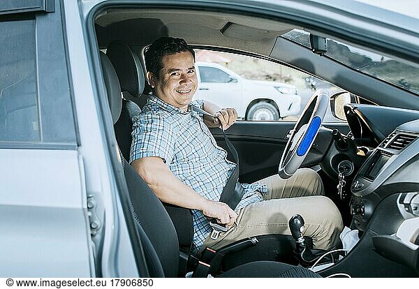 Lächelnder männlicher Fahrer beim Anlegen des Sicherheitsgurtes. Konzept eines Fahrers in seinem Auto  der seinen Sicherheitsgurt anlegt. Lächelnde Person beim Anlegen des Sicherheitsgurtes  Glücklicher Fahrer beim Anlegen des Sicherheitsgurtes