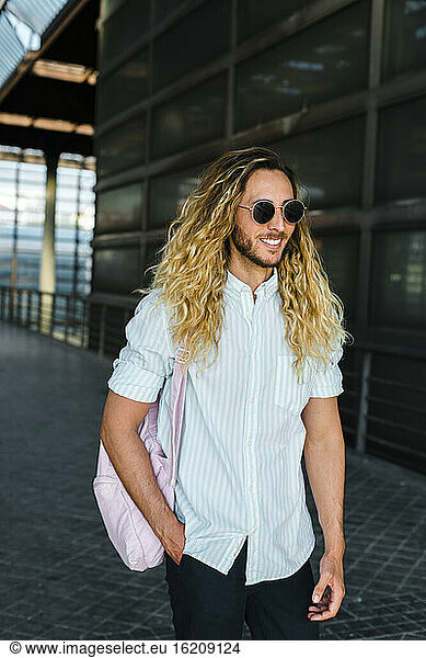 Lächelnder männlicher Hipster beim Spaziergang am Bahnhof
