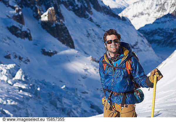 Lächelnder Mann in blauer Jacke stand still auf einem Gletscher