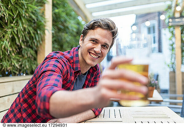 Lächelnder Mann mit Bierglas in einer Kneipe