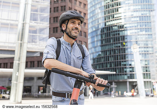 Lächelnder Mann mit E-Scooter auf dem Stadtplatz  Berlin  Deutschland