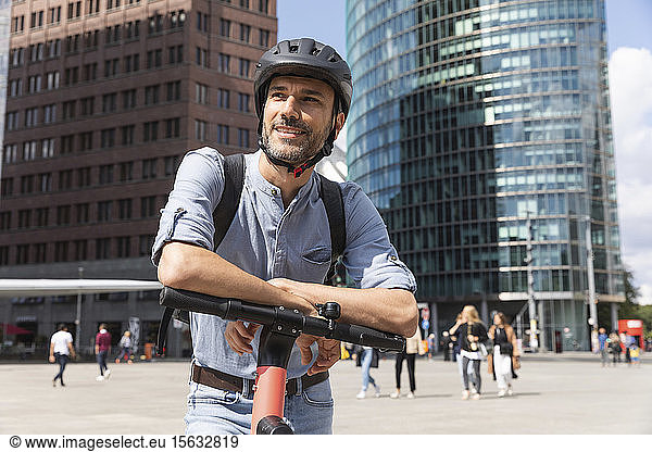 Lächelnder Mann mit E-Scooter auf dem Stadtplatz  Berlin  Deutschland