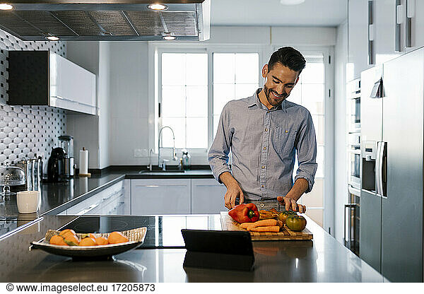 Lächelnder Mann mit Gemüse an der Küchentheke stehend