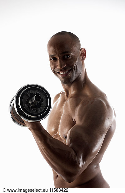 Lächelnder Mann mit nackter Brust beim Heben von Gewichten