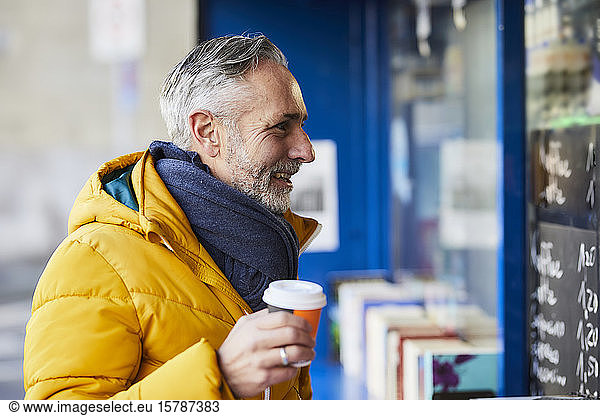 Lächelnder reifer Mann an einem Stand mit Kaffee zum Mitnehmen