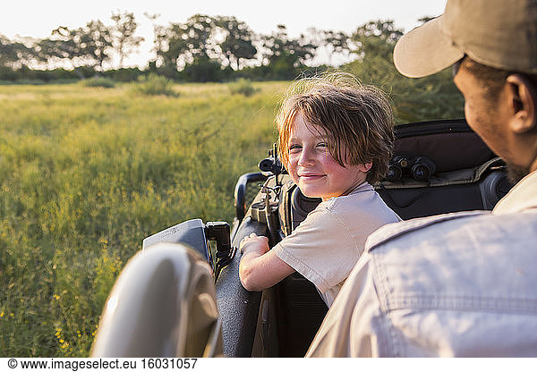 lächelnder sechsjähriger Junge lenkt Safari-Fahrzeug  Botswana