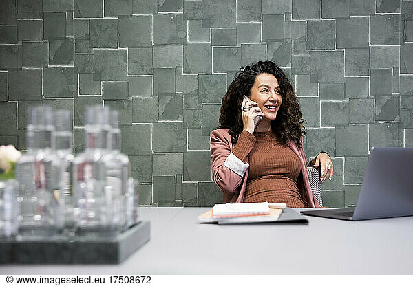Lächelnder weiblicher Chef  der mit einem Smartphone im Büro spricht