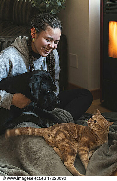 Lächelnder weiblicher Teenager sitzt mit Haustieren zu Hause