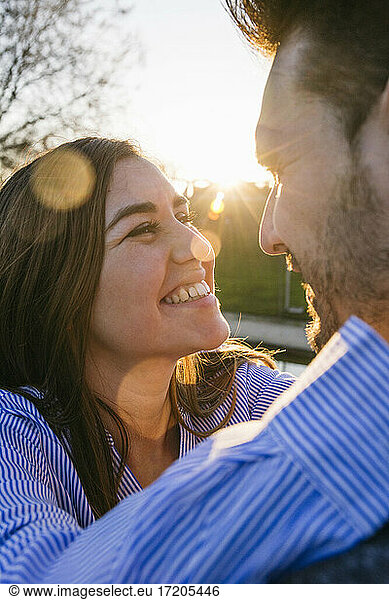 Lächelndes erwachsenes Paar  das sich bei Sonnenuntergang ansieht