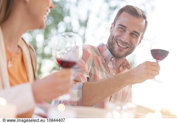 Lächelndes junges Paar trinkt Rotwein im Freien