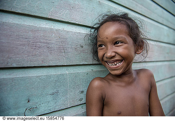 Lächelndes kleines Mädchen vom Amazonas zu Hause  im Freien