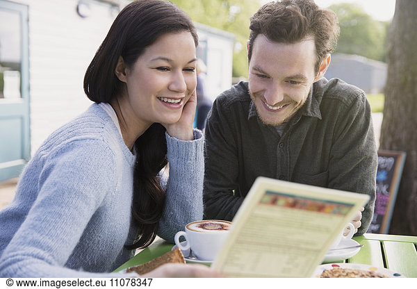 Lächelndes Paar beim Lesen des Menüs im Outdoor-Café