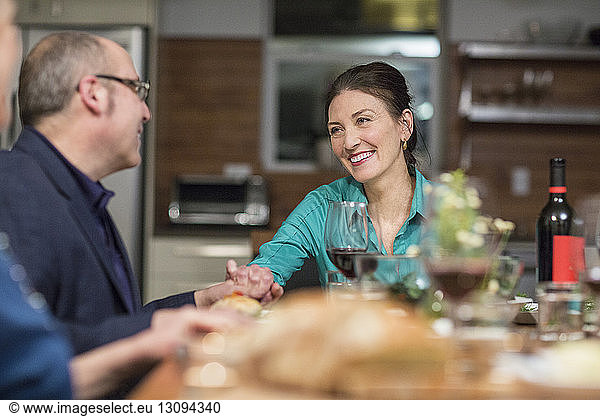 Lächelndes Paar hält sich bei geselligem Beisammensein am Tisch an den Händen