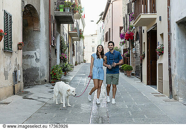 Lächelndes Paar mit Hund auf einem Fußweg in der Stadt