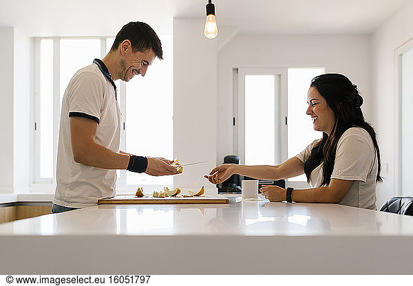 Lächelndes Paar schneidet Obst in der Küche zu Hause