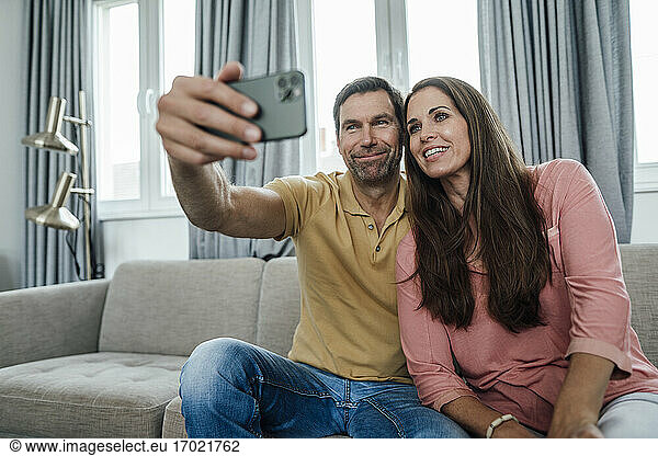 Lächelndes reifes Paar nimmt Selfie in Wohnung
