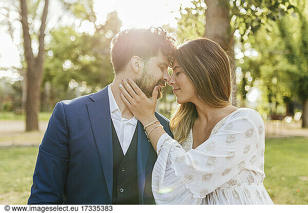 Lächelndes  zärtliches Paar mit geschlossenen Augen  das sich im Park umarmt