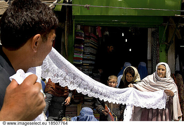 Lace and cloth vendor helps a customer at a central market in Kabul.