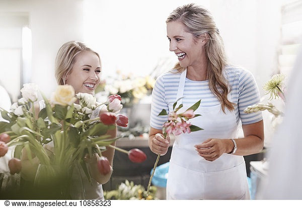 Lachende Floristen arrangieren Blumenstrauß im Blumenladen
