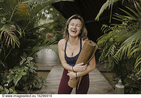Lachende Frau mit Yogamatte