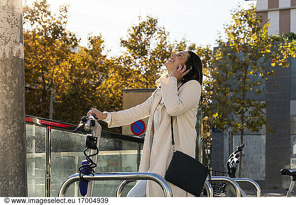 Lachende Unternehmerin an einer Bikesharing-Station