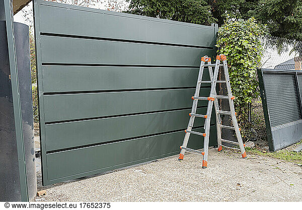 Ladder in front of green metal gate