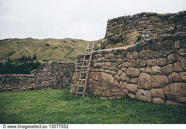 Ladder on old ruin by mountain against sky