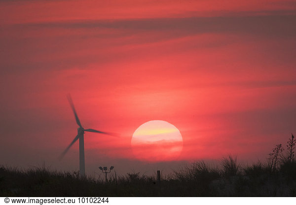 Landscape at sunrise with a wind turbine.