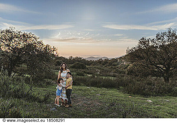 Landscape of young mother and children smiling under blue sky in field