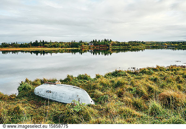 Landschaft mit einsamen Seeufern und umgestürztem Boot auf dem Land