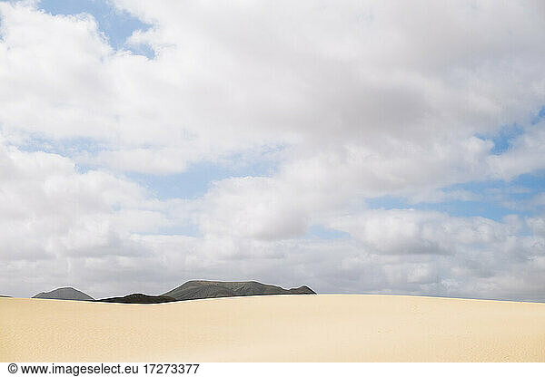 Landschaftlicher Blick auf Sandstrand gegen bewölkten Himmel
