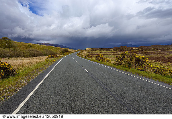 Landstraße mit dramatischen Wolken im Frühling auf der Isle of Skye in Schottland  Vereinigtes Königreich