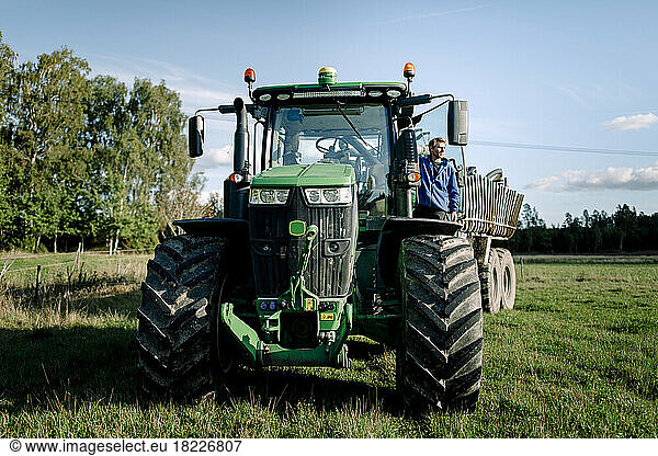 Landwirt steht auf einem Traktor auf einem Feld unter Himmel