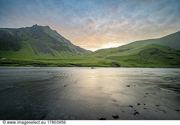 Langzeitbelichtung  Fluss Skógá vor grünen Hügeln  stimmungsvoller Sonnenuntergang  Südisland  Island  Europa