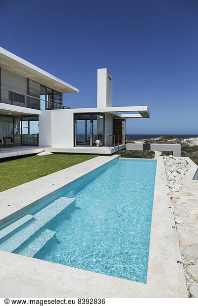 Lap pool and lawn outside modern house