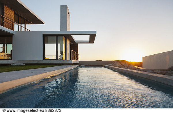 Lap pool outside modern house at sunset