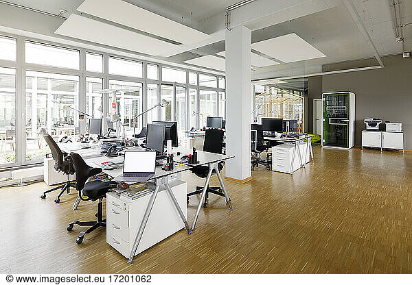 Laptop and computers on desk in empty office