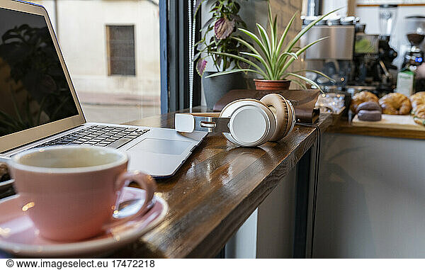 Laptop and wireless headphones on cafe table